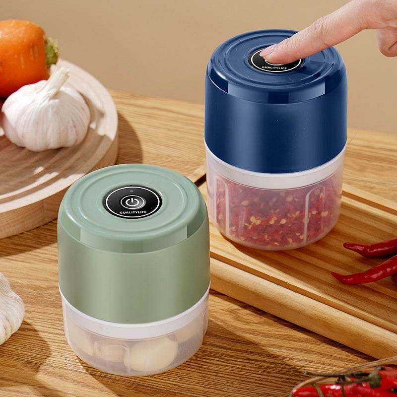 Mini electric garlic press and masher chopping garlic and vegetables in the kitchen